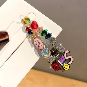 Detail of handmade colorful rhinestone hair clip featuring vibrant gems on a display card