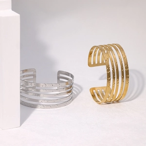 Detail of layered open cuff bracelets with hammered texture in gold and silver finish