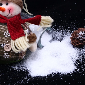 Artificial white snow powder for Christmas decor shown with snowman and pinecone