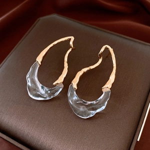 Dettaglio di orecchini a goccia in oro 18k con resina trasparente su seta marrone