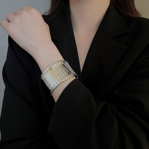 Close-up of wide silver multi-row cuff bracelet on a model wearing a black blazer