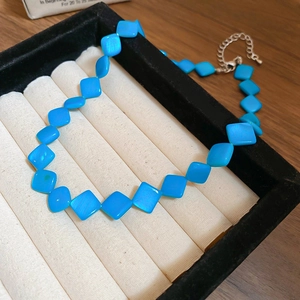 Detailed top view of blue rhombus beaded necklace with silver metal clasp in jewelry tray