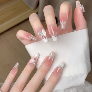 French tip press-on nails with nude pink gradient, rhinestones, and 3D butterfly charms