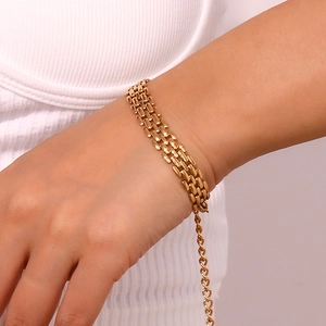 Detail of gold-plated stainless steel watch-band style chain bracelet on a wrist