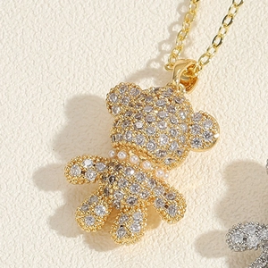 Macro view of gold teddy bear pendant with micro-pave zircons and small pearl detail