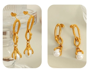 Detail of 18K gold chain earrings with teardrop pearls hanging on a glass vessel