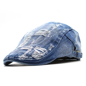 Dettaglio del berretto vintage in denim blu con fori usurati e fibbia in metallo
