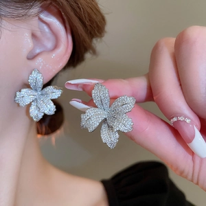 Close-up of sparkling silver flower stud earrings with zirconia stones on a model
