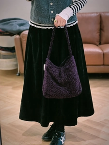 Dettaglio della borsa a spalla in tweed viola spesso con trama a maglia e etichetta laterale
