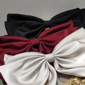 Three satin bow hair clips in black, wine red, and champagne with glossy silk texture