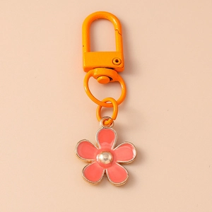 Detail view of an orange enamel flower keychain with a gold-tone lobster clasp hook