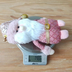 Pink plush Santa figurine weighing 148.6g on a digital scale for Christmas decor