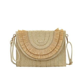 Detail of raffia woven envelope bag with tiered fringe and faux leather strap