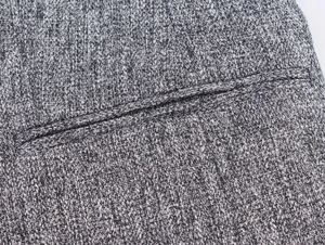 Detail shot of grey herringbone fabric texture and stitching on a casual blazer