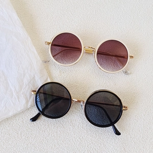 Retro round frame children sunglasses with white and black frames on minimalist background