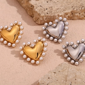 Detailed view of heart-shaped earrings with white pearls in gold and silver finish