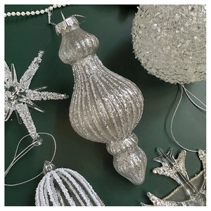 Detailed view of silver snowflake and ball ornaments on a deep green background