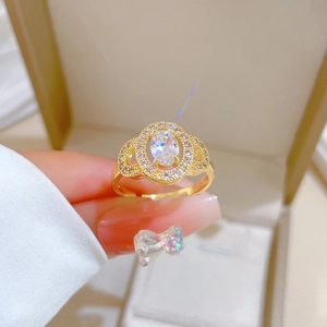 Macro detail of gold oval halo ring with adjustable band held in front of jewelry box