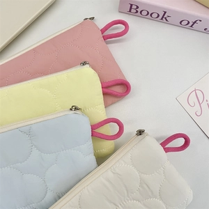 Detailed view of quilted cloud coin pouches in four pastel macaron colors with zippers