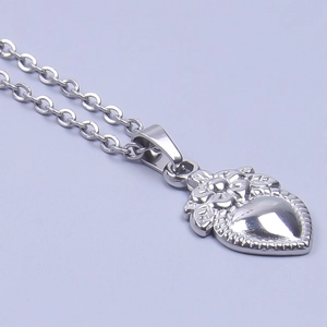 Detail of a polished heart-shaped pendant with an elegant floral relief engraving
