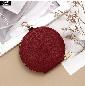 Back view of a round burgundy lychee pattern coin purse with a gold metal carabiner