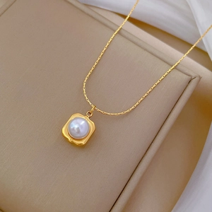 Close-up of a square gold pendant with a white pearl on a delicate titanium steel chain