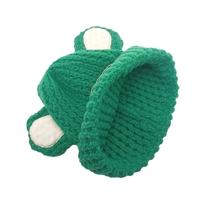 Gros plan sur un bonnet en maille épaisse verte avec oreilles d'ours et texture douce