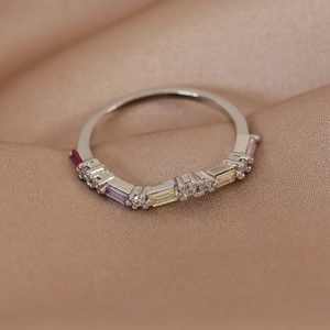 Close-up of silver ring with colorful micro-set cubic zirconia on champagne silk fabric