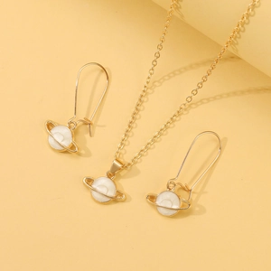Detailed close-up of golden planet earrings and necklace set with white enamel inlay