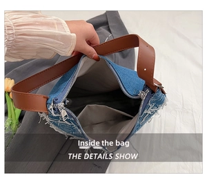 Detail view of denim tote interior showing gray lining, inner pocket and silver zipper