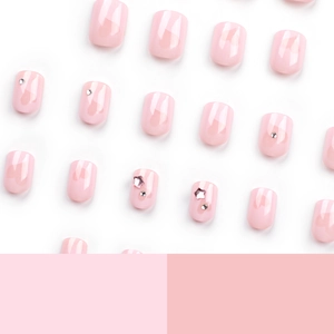Faux ongles roses avec motifs de cœur et strass présentés en ensemble complet