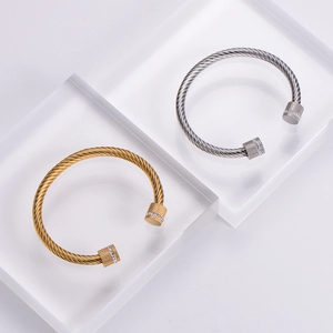 Detail of gold and silver cable bracelets with knurled end caps and white zircon stones