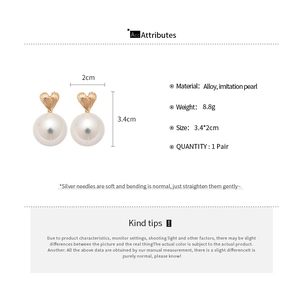 Detail of heart-shaped pearl earrings with gold texture and dimension specifications
