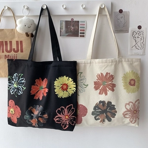Close-up of artistic floral print on black and cream canvas tote bags in a minimalist setting
