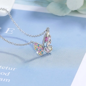 Détail d'un collier papillon en argent avec des zircons colorés sur fond décoratif
