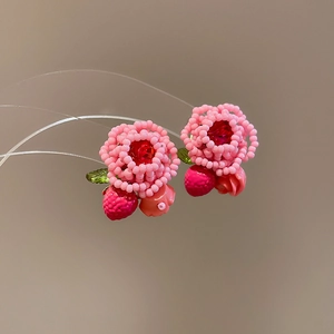 Detail of handmade pink beaded flower earrings with red strawberry and green leaf charm