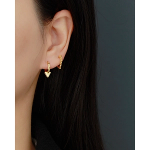 Close-up of a model wearing S925 silver heart and beaded hoop earrings in gold finish