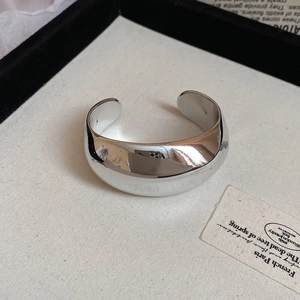 Dettaglio macro del bracciale rigido argento con superficie geometrica lucida