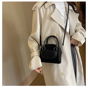 Detail of black leather handbag featuring a plush faux fur flap and silver metal buckle
