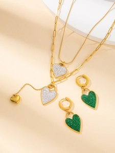 Details des goldenen Herz-Schmucksets mit doppelter Halskette und grünen Ohrringen