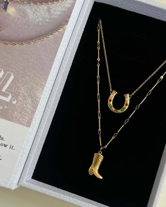 Macro shot of gold horseshoe necklace with colorful gems and western boot pendant charm