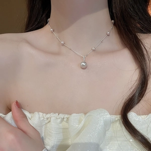 Close-up of elegant pearl pendant necklace worn on neck with silver chain detail