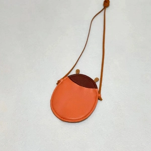 Detail of cute ladybug-shaped orange leather kids crossbody bag with stitch craftsmanship