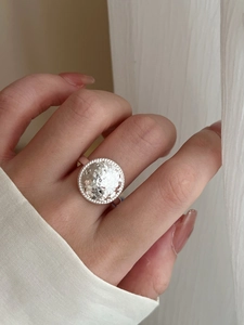 Macro detail of the hammered silver disc ring featuring a handcrafted textured surface