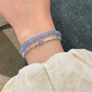 Gros plan de bracelets en aigue-marine et perles d'argent sur poignet avec fond en jean