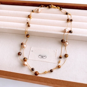 Detail of vintage double-layer necklace with tiger eye stones and pearls in a wooden box