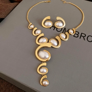 Detail of gold-tone tassel jewelry set with oval pearls on brand gift box packaging