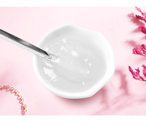 Macro shot of thick transparent lip gloss base gel in white bowl with metal spoon
