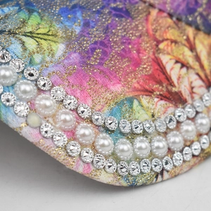 Détail macro du bord d'une casquette avec imprimé floral, perles et strass scintillants