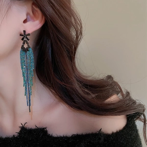 Close-up of long tassel earrings with blue-green rhinestones on a model side profile
